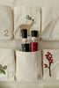 The textile advent calendar includes embroidered pockets adorned with numbers and festive motifs, such as a deer and red berries. Pocket number six contains two "Wooden Soldiers" peg dolls, one dressed in green and the other in red, both wearing small black hats.