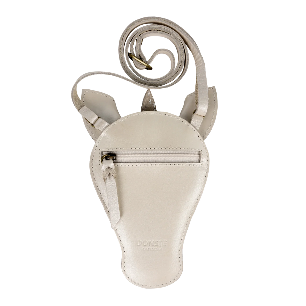 The Donsje Leather Blinc Purse - Unicorn is a light beige metallic leather crossbody pouch with a rounded shape, front zipper pocket, signature ear-like details, an adjustable strap, and "DONSJE" embossed near the bottom.