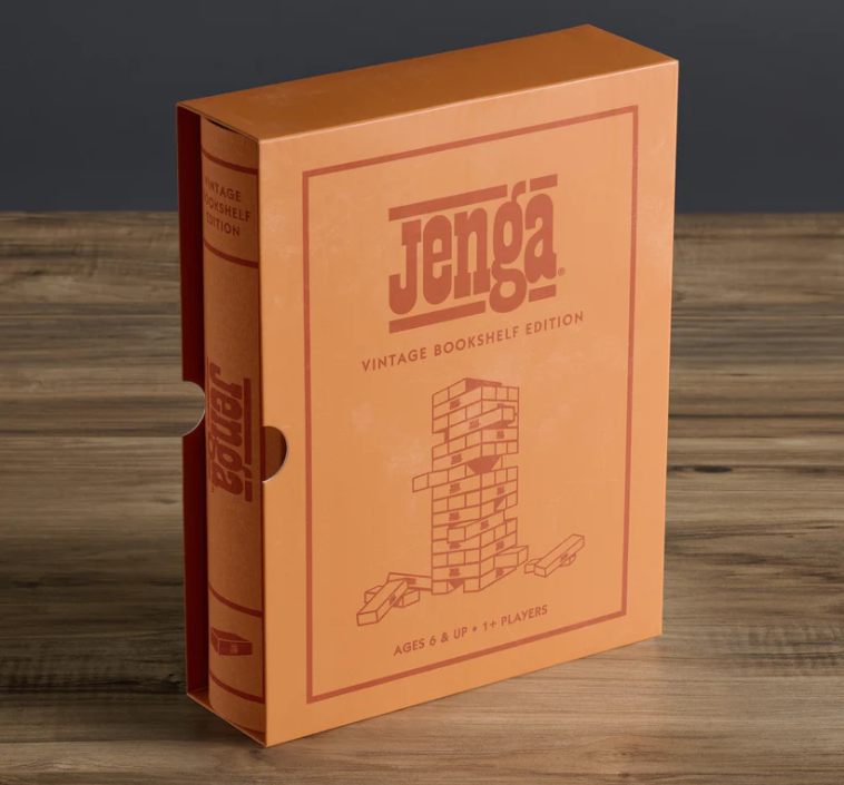 The Jenga Vintage Bookshelf Edition stands upright on a wooden surface in its orange box, featuring minimalist line art of the classic game—an ideal piece to enhance your family game night display.