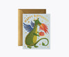 The Birthday Dragon Card features a green dragon breathing fire onto a cake, metallic gold foil stars, and "Happy Birthday!" above. The blank interior lets you add your own message. Comes with a brown envelope.