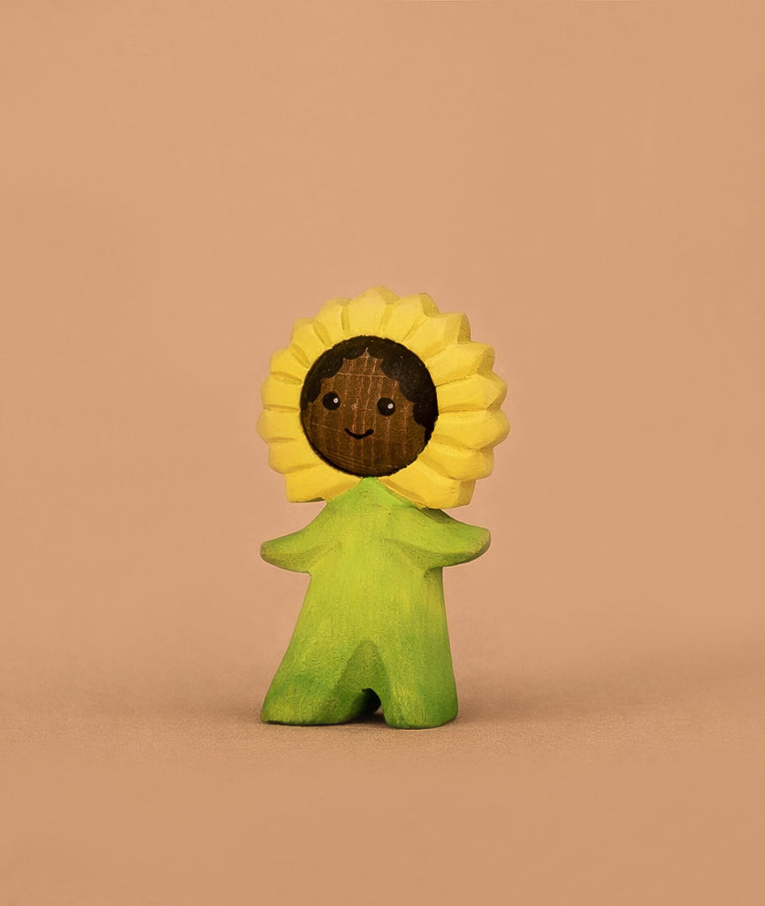 The Bumbu Handmade Wooden Flower Child Sunflower is a small wooden figurine with a smiling face, yellow sunflower headpiece, and green outfit—a charming Waldorf toy for imaginative play. Ships in one week.