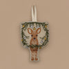 The Togetherness Deer Ornament features a fawn surrounded by a garland of green branches and ornaments, elegantly hanging on a loop against a beige backdrop.