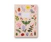 This pale pink ruled notebook features colorful illustrations of flowers, leaves, butterflies, beetles, a ladybug, and cherries. A white label with gold "Notebook" lettering accents the cover. Part of the Assorted Set of 3 Curio Notebooks.