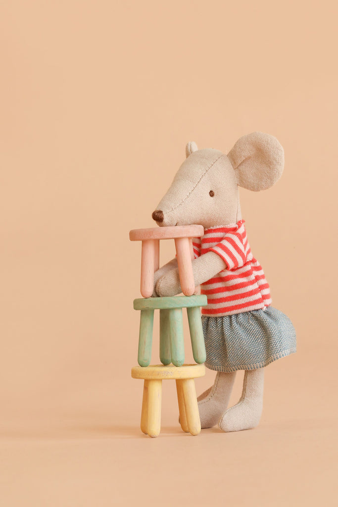 A stuffed mouse stands upright, stacking Maileg Stool Set, Mouse - Mint/Light Yellow stools with a vintage paint finish against a peach-colored background.
