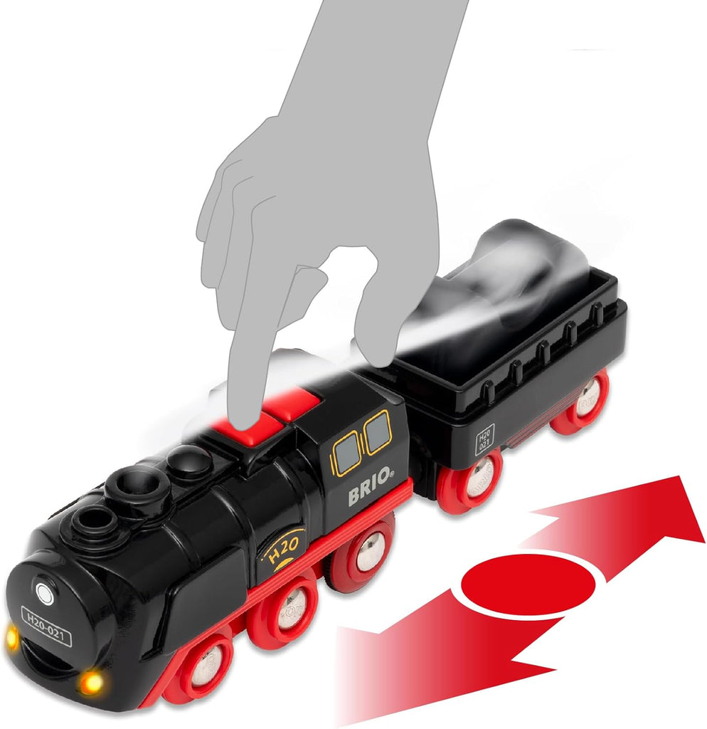 A hand presses a red button on the black and red BRIO World Christmas Steaming Train Set, labeled "BRIO," with smoke at the back and red arrows showing movement—perfect for festive train set adventures.