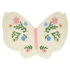 The Meri Meri Butterfly Wings pillow features a butterfly shape in cream natural cotton with ruffled edges, colorful embroidered flowers and green leaves on the wings, and a pink stripe at the center resembling a butterfly's body.