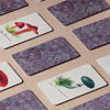 Several rectangular cards from the Memory Game - Fungi are laid on a surface, some face-down with a purple marbled pattern, others face-up showing colorful vintage fungi illustrations.