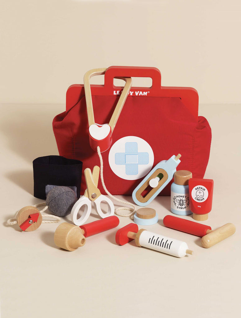 The Pretend Play Vintage Doctor Set includes a red doctor's bag with a blue cross and wooden medical tools—syringe, stethoscope, scissors, thermometer, pill bottles, medicine tube, bandage, and otoscope—for endless role play fun.