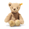 The Thommy Teddy Bear Brown Plush Toy, 8 inches, features light brown plush fur, black eyes, a dark brown stitched nose, and a yellow tag in its left ear. It sits upright, shown against a white background.