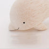 A close-up image of a handmade tiny wooden dolphin figurine, hand-carved from eco-responsible forests, with a smooth texture and a minimalistic design, featuring a small smile.