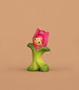 The Bumbu Handmade Wooden Flower Child Tulip, featuring a smiling face with a pink flower hat and green petal outfit, stands upright against a beige background—perfect for open-ended play. Ships in one week.