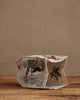 The Coral & Tusk Snow Day Tissue Box Cover, featuring embroidered snowmen, a reindeer, and a star, adds festive charm to your snow day decor on any wooden surface or against a neutral beige wall.