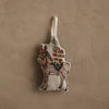 Coral & Tusk Christmas Donkey ornament embroidered on natural linen, featuring a small pine tree and colorful wrapped gifts strapped to its back.