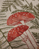 The Coral & Tusk Mushrooms and Ferns Lumbar Pillow showcases linen fabric embroidered with red mushrooms, white spots, and green fern leaves for a botanical, nature-inspired accent.