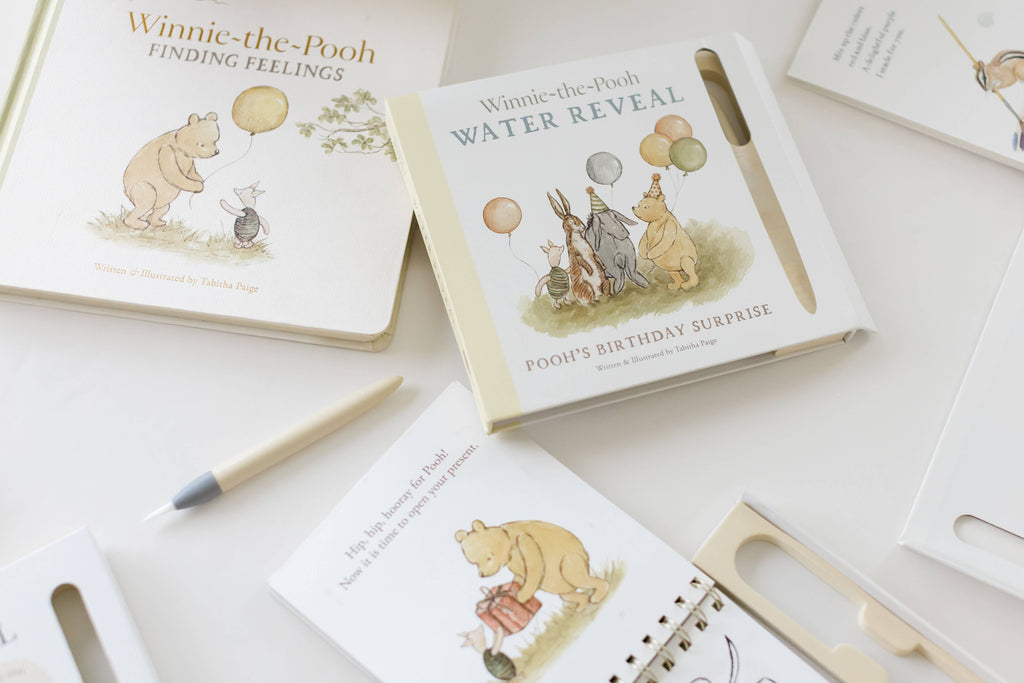 Two illustrated children’s books, including Winnie-the-Pooh: Pooh’s Birthday Surprise (Water Reveal) with a water reveal pen, displayed on a white surface as a no-mess activity book.