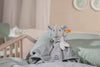 The “My First Steiff” Ellie Elephant Security Blanket Baby Toy, 10 Inches, with a striped scarf and embroidered blanket, rests on a mint-green bed in a softly lit nursery.