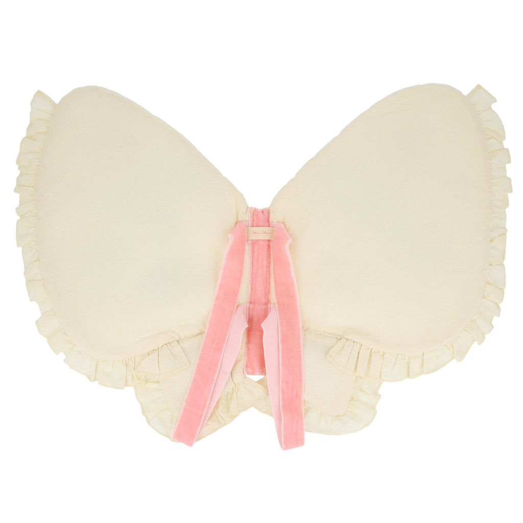 The Meri Meri Butterfly Wings is a cream-colored, butterfly-shaped pillow with ruffled edges, two pink velvet ribbons crossing at the center, and delicate embroidered flowers on natural cotton for extra charm.
