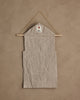 The Coral & Tusk Christmas Clock Advent Calendar is a beige fabric wall hanging with pockets, displayed on a wooden rod and string, featuring a small white tag with a red tree design at the top against a tan textured wall.