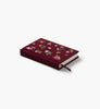 The Gracie Mini Embroidered Journal, with a maroon cover adorned with colorful floral embroidery and a matching ribbon bookmark, lies on a white background—ideal as a blank unlined hardcover for capturing your creative thoughts.