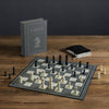 Chess Vintage Bookshelf Edition: A classic strategy game featuring white and black pieces on a board, a standing chess instruction book, and two drawstring bags—all elegantly arranged for collectors.