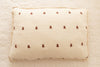A rectangular pillow with the Organic Cotton Layered Gauze Pillowcase - Teddy, featuring a cream color and small brown teddy bears, rests on a quilted white bedspread.