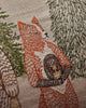 Close-up of a Coral & Tusk Christmas Cheer Lumbar Pillow, a linen lumbar pillow embroidered with a fox holding a small, round object between two pine trees.