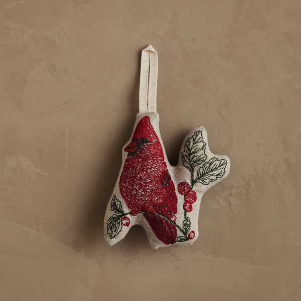 Coral & Tusk Red Cardinal Ornament featuring an embroidered bird perched on a branch with red berries on natural linen, finished with a cream-colored hanging loop.