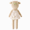 Cuddle + Kind Amelia The Cow—a beige knitted stuffed animal with upright ears, small horns, a green headband, cream dress, and short tail—is a charming handmade and sustainable doll, shown from the back on a white background.