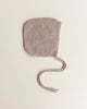 A single Handmade Merino Wool Newborn Bonnet in Sand, made of extra fine Italian merino wool, with long ties, placed against a plain light background.