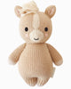 The Cuddle + Kind Baby Pony is a hand-knit beige plush toy made from soft Peruvian cotton yarn, with cream accents, black stitched eyes, a smiling face, blush cheeks, a yarn mane, and cuddly round arms and legs.