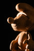 In a dimly lit setting, a wooden statue called "Smurf, Oak" depicts a cartoon mouse with large ears and distinctive nose, boasting smooth carving and intricate details reminiscent of Smurf Village craftsmanship.