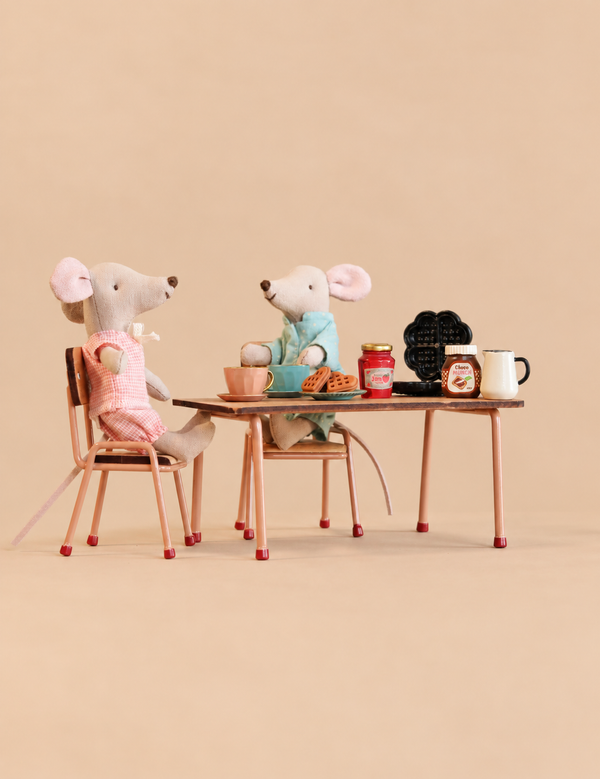 Two Maileg mice sit at a Maileg Breakfast Table Set featuring miniature cups, plates of waffles, a jar of jam, a chocolate spread, a waffle iron, and a pitcher.