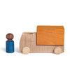 A Lubulona Wooden Truck - Ochre with a yellow block rests beside a small, blue-bodied wooden figure with a brown head—eco-friendly toys displayed on a white background.