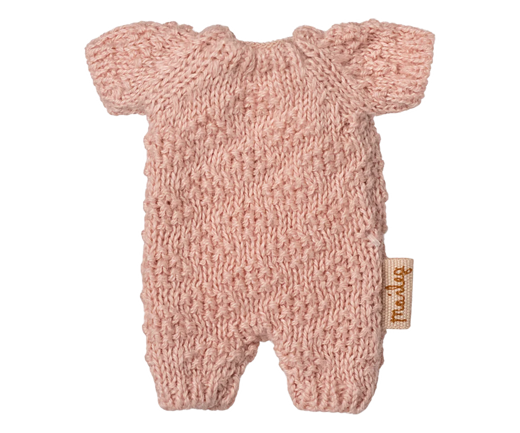 The Maileg Extra Clothing: Knitted Suit, Micro - Rose for Micro Bunny is a small pink knitted romper with short sleeves and legs, shown flat on a white background. A small tan fabric tag accents the side.