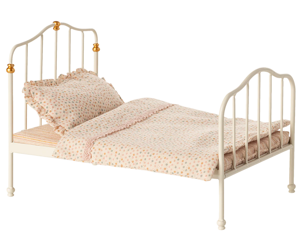 PRE-ORDER: Vintage Bed, Mouse Size - Off White. This small metal bed for mice features gold accents and comes with a ruffled pillow and pastel polka dot bedding on Maileg fabrics. Estimated ship date: Early October.