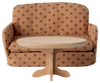 A PRE-ORDER: Oval Coffee Table, Mouse - Nature (Estimated Ship Date: Early October) from SuitCasa sits in front of a miniature beige couch with brown polka dots.