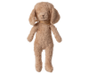 The Maileg Poodle Dog, Vintage Plush in Dusty Powder stands upright against a plain white background. This soft puppy toy features floppy ears, dusty powder-colored fur, and a brown scarf around its neck.