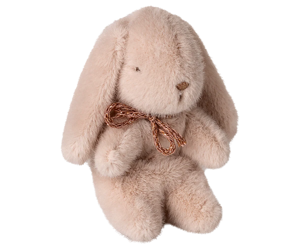 The Maileg Plush Bunny, Mini - Light Powder, is a soft stuffed animal in light powder recycled polyester, featuring floppy ears, simple stitched facial features, and a brown ribbon bow around its neck. It sits upright against a white background.