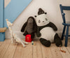 Three safari friends—a giraffe with colorful dots, a Maileg Gorilla (Medium), and a large soft panda—sit on a wooden floor by a blue chair and staircase, with small toy cars and a red block numbered 1 nearby.