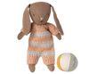 The Maileg Micro Bunny With Ball - Brown - Dusty Rose (Magnetic Hands) sits beside a small round fabric ball with white, yellow, and gray segments—a charming storytelling toy on a white background.