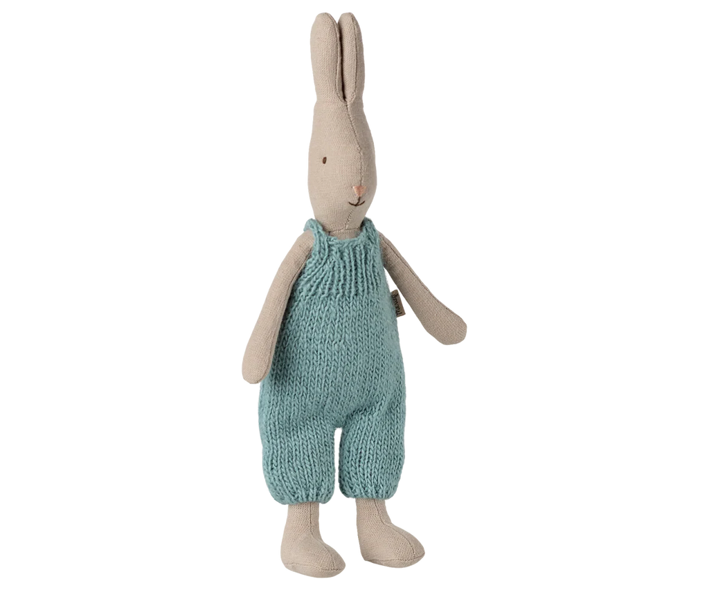 The Maileg Rabbit, Size 1 - Classic, wears light blue knitted overalls and stands upright—crafted from natural fabrics, it's ideal for a miniature dollhouse. Expected arrival: 02/15/26.