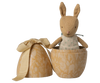 The Maileg Easter Egg with Micro Rabbit, Small - Cream Yellow, features a soft rabbit in a light green dress, presented in a decorative, yellow egg-shaped box with a matching floral-patterned lid and bow.