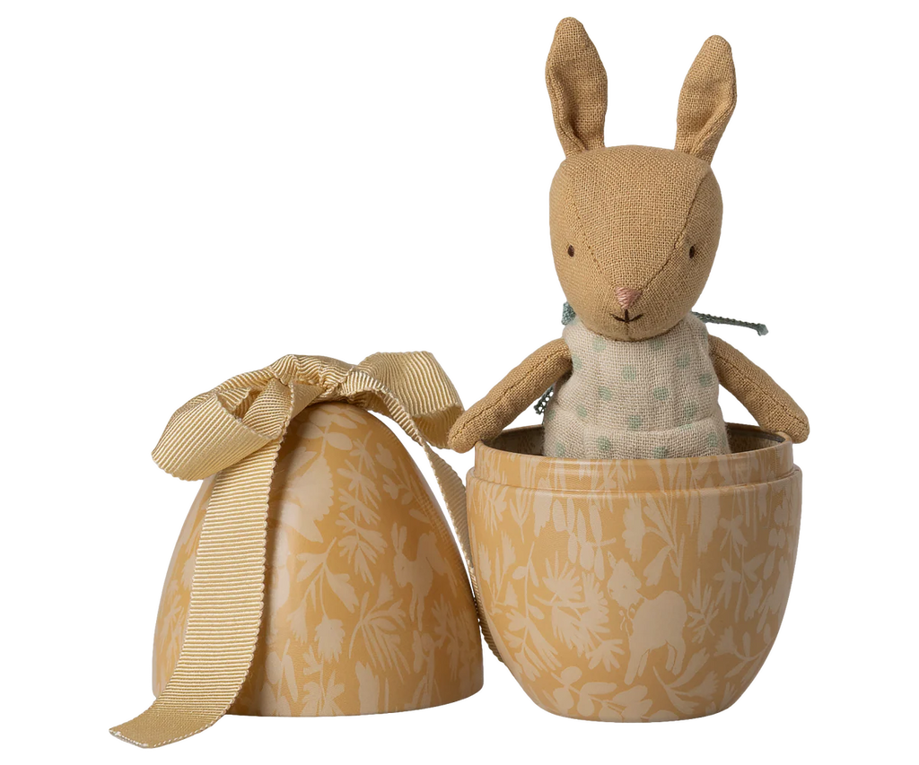 The Maileg Easter Egg with Micro Rabbit, Small - Cream Yellow, features a soft rabbit in a light green dress, presented in a decorative, yellow egg-shaped box with a matching floral-patterned lid and bow.