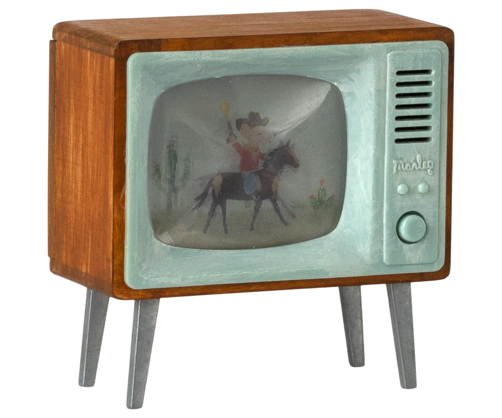 The Maileg Television, Mouse (expected 03/15/26) is a small, vintage-style wooden toy TV with metal legs and a green screen showing a cowboy on horseback. "Analog" appears near the speaker, making it perfect for miniature home decor.