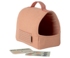 The Maileg Pet Carrier - Coral, a soft pink carrier with a handle and side pocket (expected by 02/15/26), sits beside a small pet journal and sticker sheet—stylish accessories arranged on a light background.