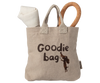 The Maileg Pet Supply, Toys: A beige tote bag with “Goodie bag” and a cartoon dog print, ideal for puppy accessories or a magnetic puppy bone, with a rolled white cloth and textured tan loop handle (arriving 03/15/26).