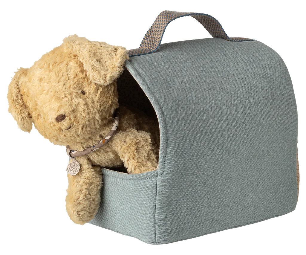 The Maileg Pet Carrier - Dusty Blue (expected 02/15/26) features a plush teddy bear with a collar, nestled inside a light blue carrier with a handle—perfect for displaying your favorite pet accessories.