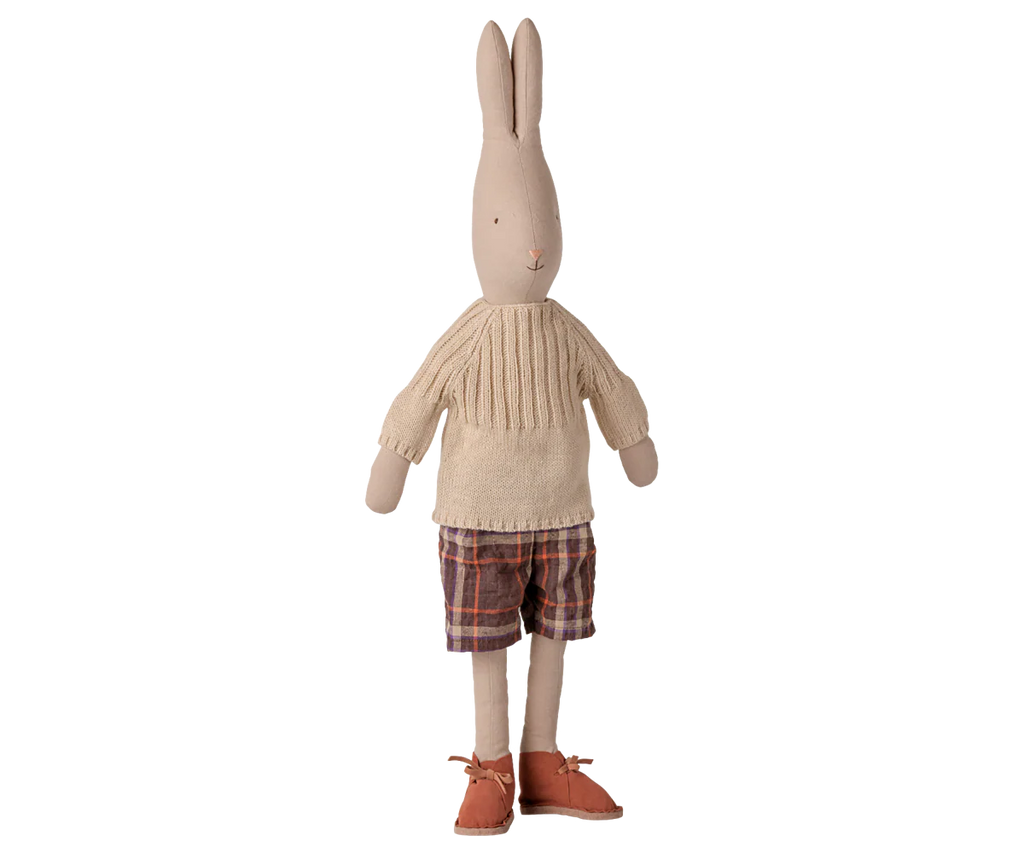 The PRE-ORDER: Maileg Rabbit, Size 4 - Classic, features pants and a knitted sweater. This charming stuffed toy stands upright against a white background, highlighting its stylish natural fabrics. Estimated arrival: Early November.
