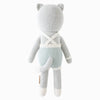 Cuddle + Kind Dylan the Kitten is a hand-knit gray stuffed cat shown from the back, wearing blue and white striped overalls with white suspenders, a tail, round ears, and white accents on its hands, feet, and suspenders.