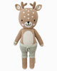 Cuddle + Kind Elliott the Fawn is a sustainable, fair trade, hand-knit plush doll featuring antlers, a light brown body with white spots, and light green drawstring pants, shown upright against a white background.